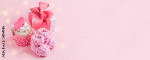 Fototapeta Naklejka Na Ścianę i Meble -  Cute newborn baby girl shoes with festive decoration cupcake and gift box  over pink background. Baby shower, birthday, invitation or greeting card idea, copy space, flyer, invitation, monochrome