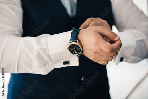 primo piano di un uomo  vestito in giacca e cravatta che sistema il suo orologio da polso  photo