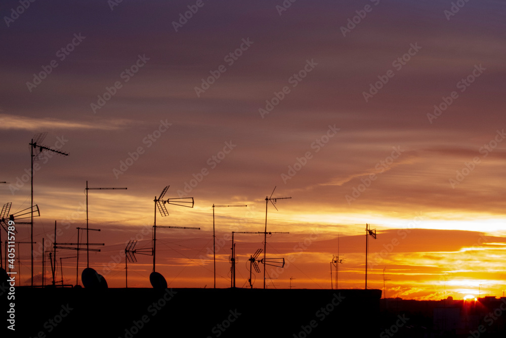 Obraz premium Sunset in the city with antennas on the roofs