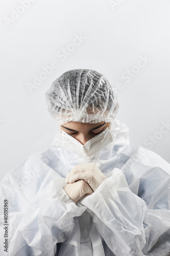 A doctor in protective wear praying. Nurses stand on to pray. Covid Combat Fatigue. Health care workers are experiencing Covid-19 burnout