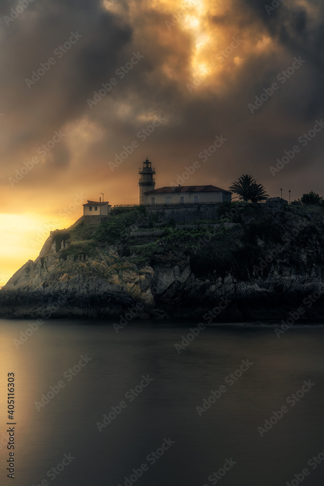 Lighthouse on a cliff with sunrise clouds