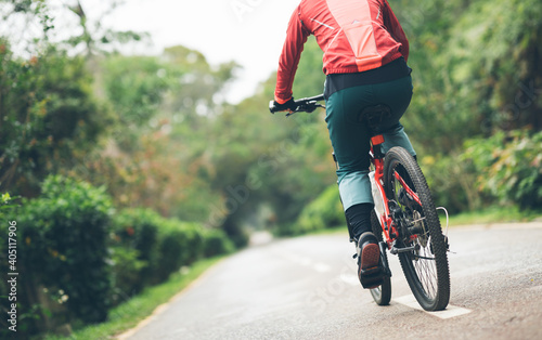 Woman cyclist riding a bike on tropical park trail in spring