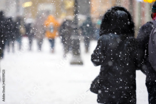 People crossing the street, snow storm. Pedestrians in the city during a severe blizzard. Focus on foreground snowflakes