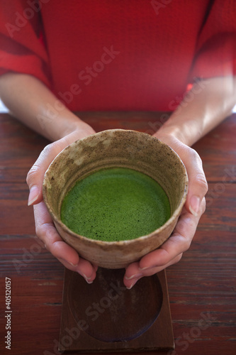 Hand hold Matcha green tea cup on the table