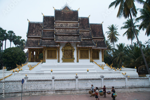 Luang Prabang Province, Laos - January 4, 2021 - Landscape of Haw Pha Bang Temple in the Morning. Laotian Women Walking Pass Haw Pha Bang Temple.