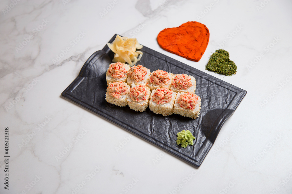 Top view of sushi roll with roasted salmon on top wrapped in rice, sesame seeds served on black plate with wasabi. hearts of turmeric and basil spices on marble background
Top view of sushi roll with roasted salmon on top wrapped in rice, sesame seeds served on black plate with wasabi. hearts of turmeric and basil spices on marble background