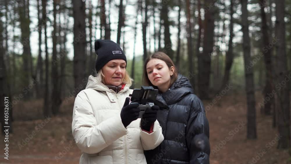 Caucasian woman with adult daughter flying aerial drone in autumn forest. Caucasian woman with adult daughter flying aerial drone in autumn forest.