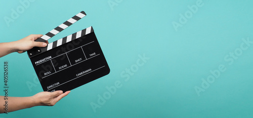 Foto Hand is holding Black clapper board or clapperboard or movie slate on mint green or Turquoise background