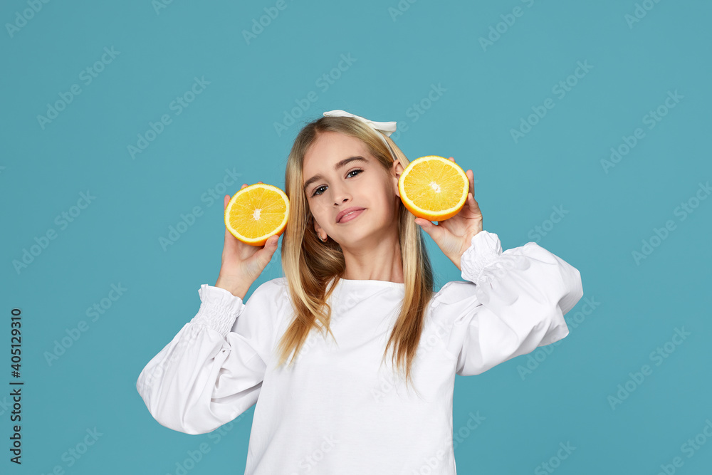 cute little child girl holding fresh juicy orange and having fun isolated over blue background cute little child girl holding fresh juicy orange and having fun isolated over blue background