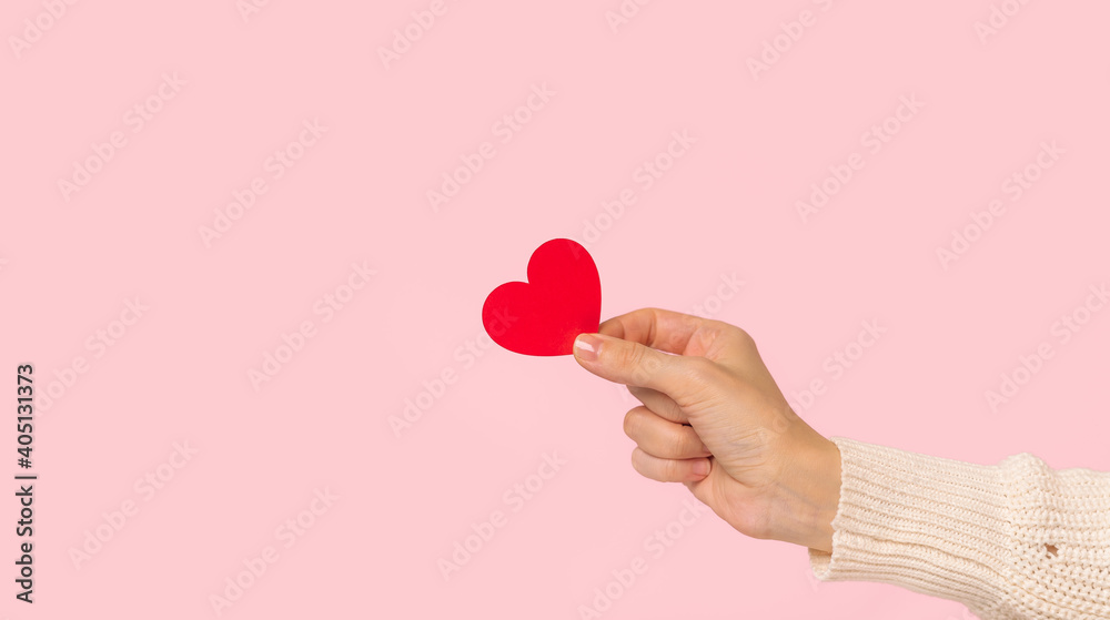 Woman hands holding red heart on pink background Woman hands holding red heart on pink background