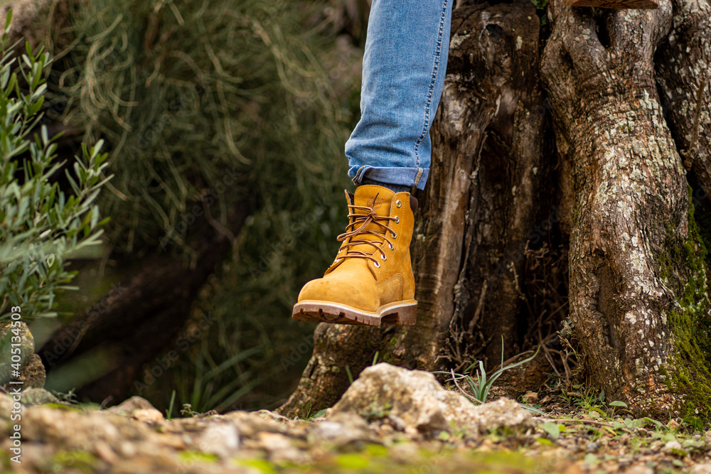close-up winter boots for man in a forest ,man sitting on olive tree , mediterranean landscape , cool leather boots close-up winter boots for man in a forest ,man sitting on olive tree , mediterranean landscape , cool leather boots