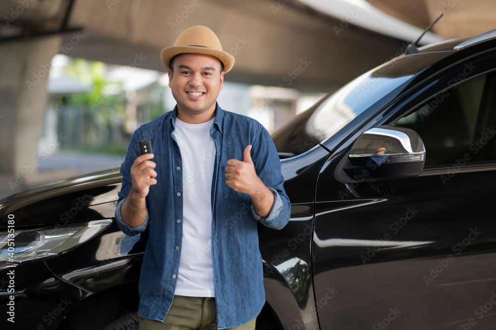 Young handsome asian man getting the new car.He showing car key and very happy. Buy or rent a car concept.