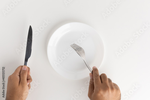 A man with a knife and fork to eat on the plate