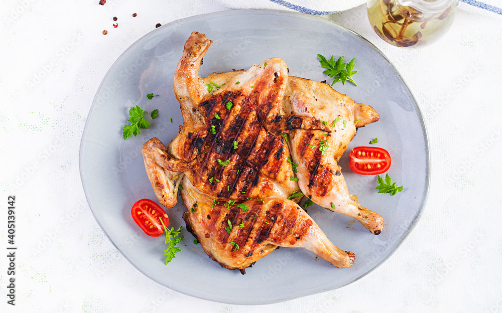 Grilled chicken Tabaka on blue plate. Georgian cuisine. Top view, above Grilled chicken Tabaka on blue plate. Georgian cuisine. Top view, above