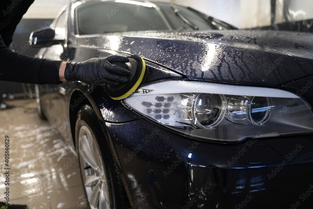 Man cleans car body with disc sponge. Preparing auto for polishing. Detailed car wash