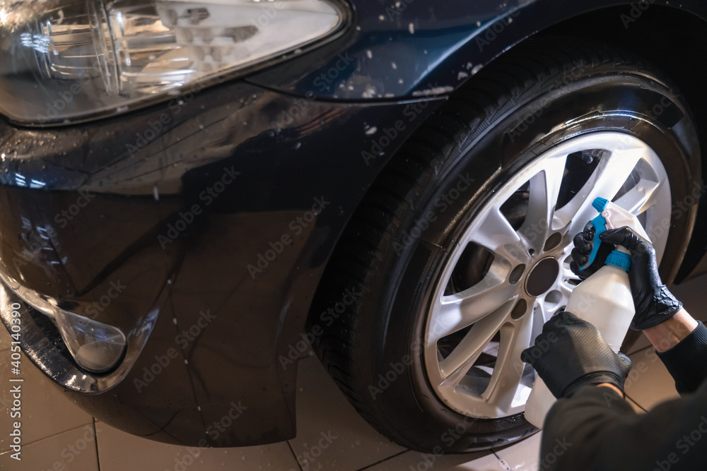 Car wash worker sprays wheel rim cleaner. Professional car detailing