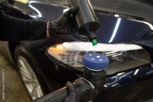 Detailing master applies car polish paste to the polisher. Vehicle paintwork polishing concept