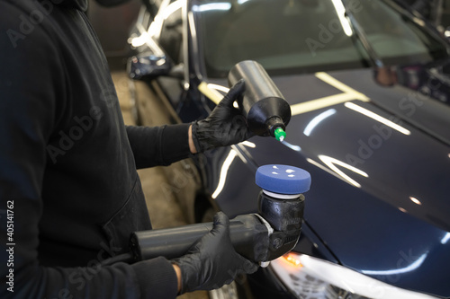 Detailing master applies car polish paste to the polisher. Vehicle paintwork polishing concept