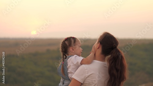 Kid and mama are having fun in the park. Mom plays with little girl in her hands. Mother and beloved child have fun together. Happy family. Walking outdoors with your baby