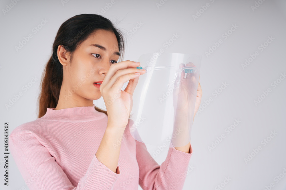 New normal fashion portrait. Asian thai long dark hair woman holding face shield isolate over white. New normal fashion portrait. Asian thai long dark hair woman holding face shield isolate over white.
