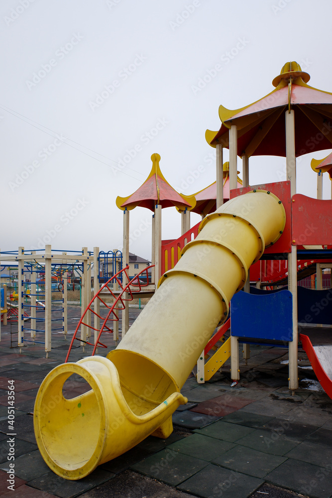 Children's wooden playground with slides and swings in the park in winter.