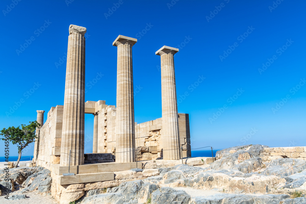 ruins of the ancient acropolis temple building in the greece city of lindos rhodes on a sunny day with plain blue sky background