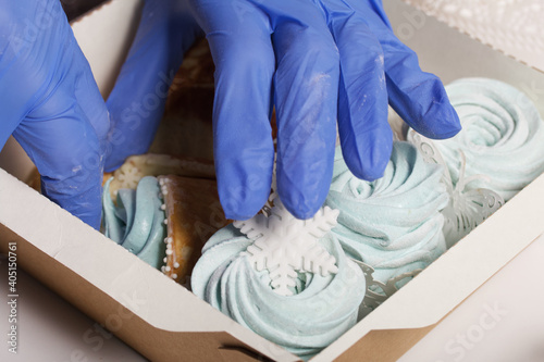 A woman in rubber gloves lays homemade marshmallows in a gift box. Close-up shot.