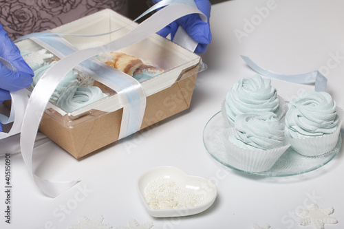 Woman in rubber gloves makes marshmallows. Packs in a gift box and ties with a ribbon. Close-up shot.