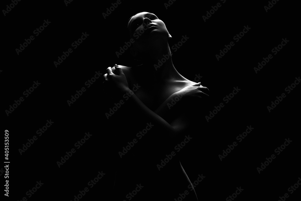 Fototapeta premium Nude Woman silhouette under light in the dark