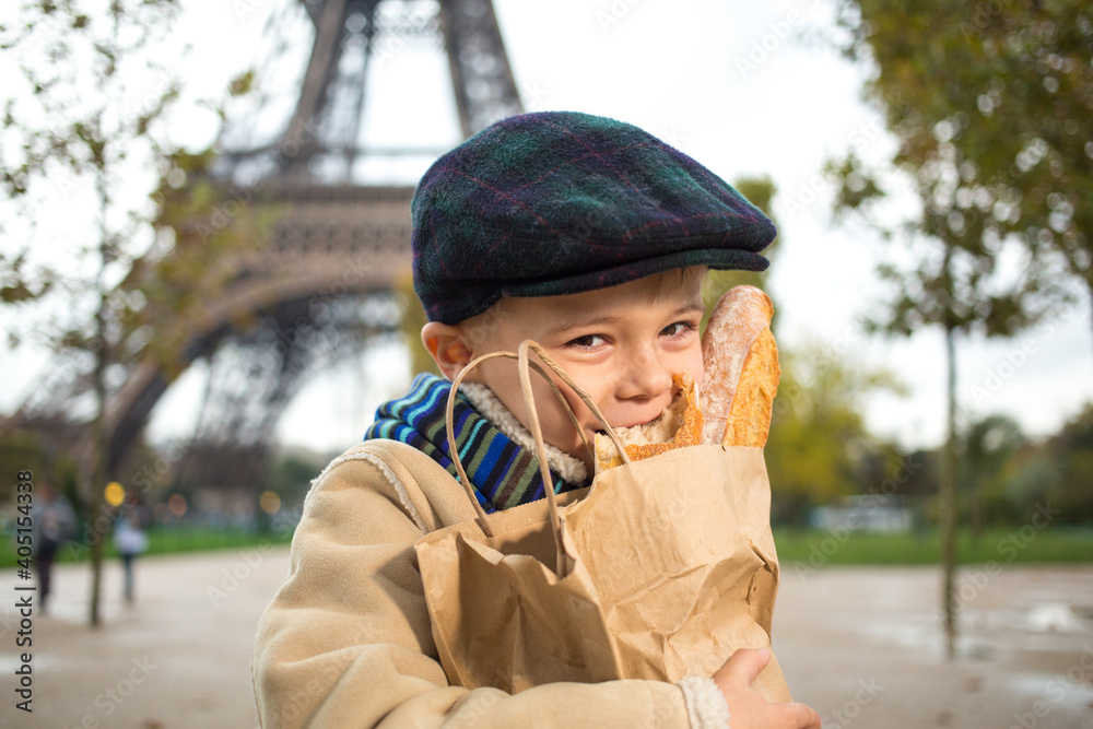 Adorable small boy eating a ffrench bread over Eiffel tower