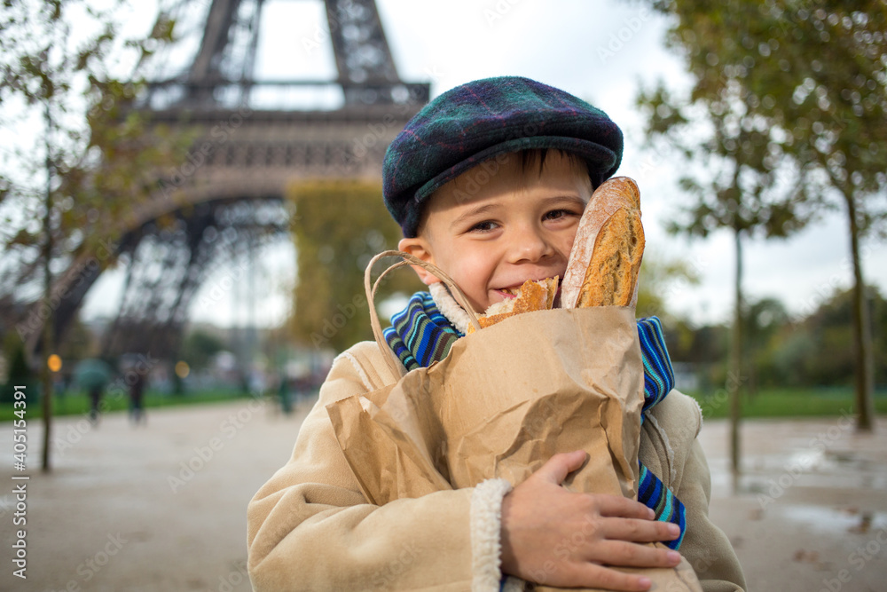 Adorable small boy eating a french bread over Eiffel tower Adorable small boy eating a french bread over Eiffel tower