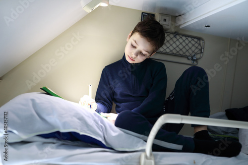 Boy on top shelf of train compartment