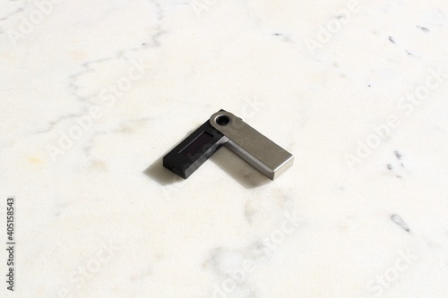 Cryptocurrency hardware wallet isolated on white marble surface. Selective focus, soft focus at the background