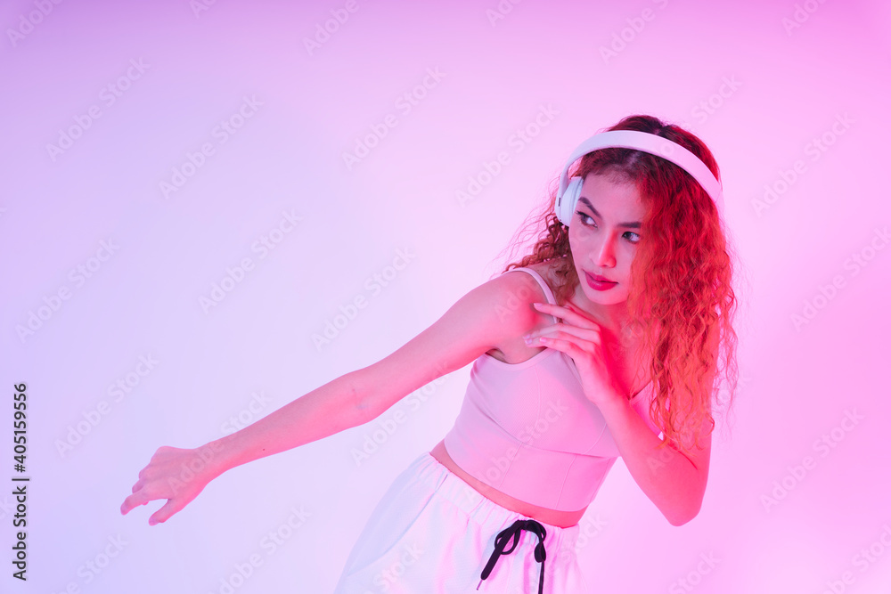 Asian girl in pink cloth listen to music and dance isolate on neon light background.
