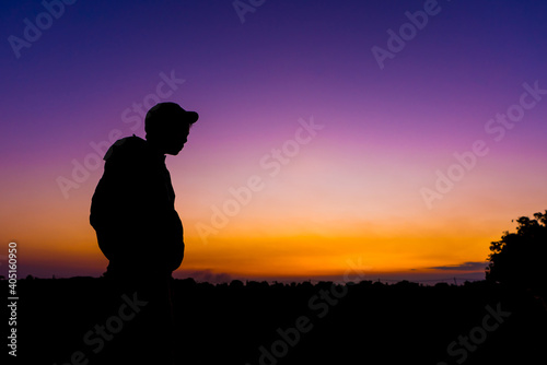 silhouette dark young man wearing hat standing emotioning with evening Twilight sky with cloud in the winter season at sunset Abstract background.Copy space for your © Akira Kaelyn