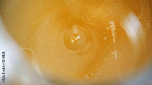 Vegetable oil drips into the container. Close-up.