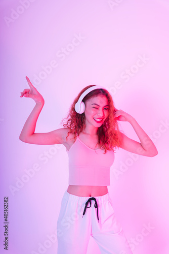 Asian woman wearing headphone and dance in neon light background.