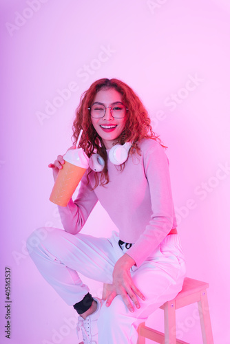 Asian woman curly hairstyle wearing eyeglasses and handphone holding beverage cup.