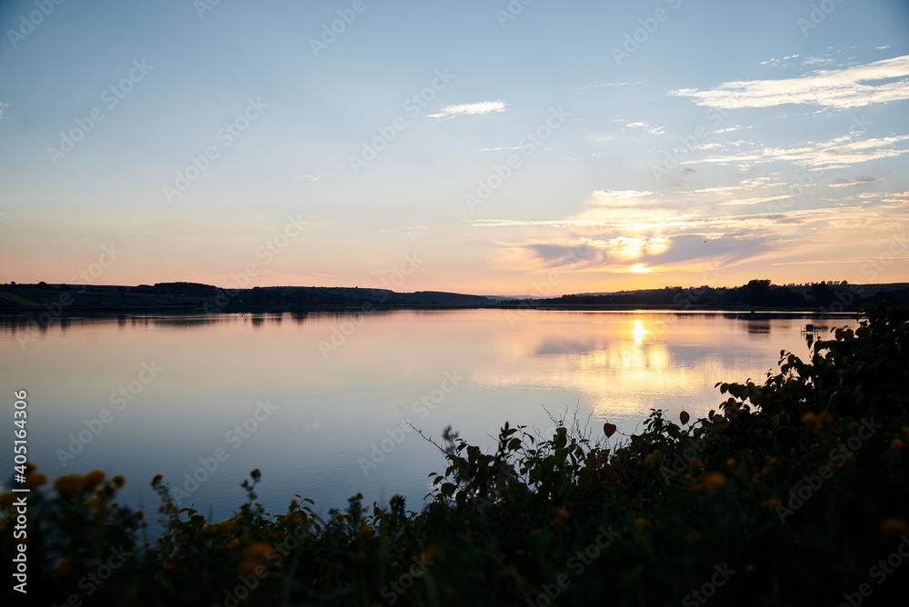 Beautiful lake view during sunset with blue and yellow sky reflection in water. Rural scene. Ecological protection and eco tourism concept. Natural landscape. Isolation in countryside.