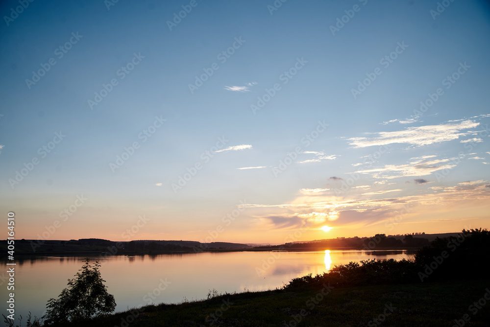 Beautiful lake view during sunset with blue and yellow sky reflection in water. Rural scene. Ecological protection and eco tourism concept. Natural landscape. Isolation in countryside.