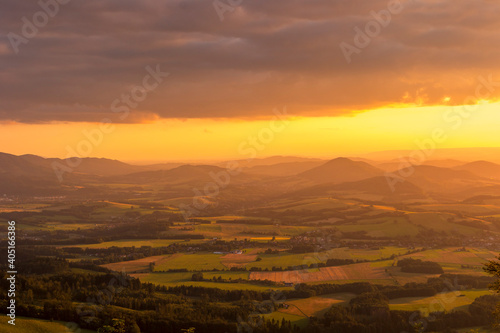 A view of a landscape full of mountains during a golden sunset with the sun on the horizon and a view of the sun from the top of Mount Ondrejnik. © Lukas