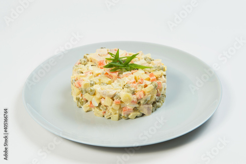 Close up of Russian traditional holiday Olivier salad. Dish of boiled vegetables dressed with mayonnaise sauce. Christmas New Year cold dish served on gray plate. Object isolated on background.
