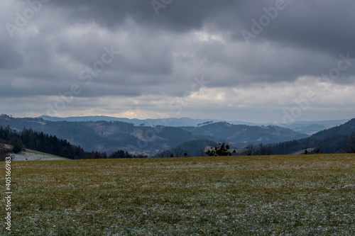 Winter landscape covered with light snow with sky and clouds in the background during a dark afternoon. © Lukas