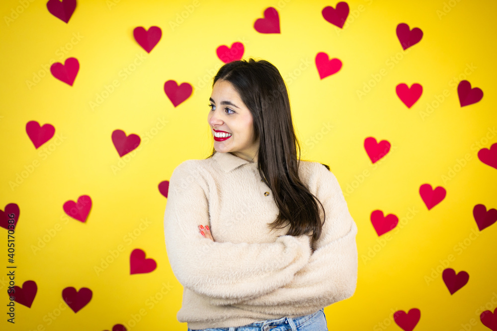 Young caucasian woman over yellow background with red hearts looking to side, relax profile pose with natural face and confident smile. Young caucasian woman over yellow background with red hearts looking to side, relax profile pose with natural face and confident smile.