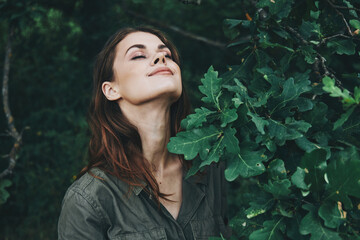 Portrait of a woman Eyes closed enjoying nature green leaves summer 
