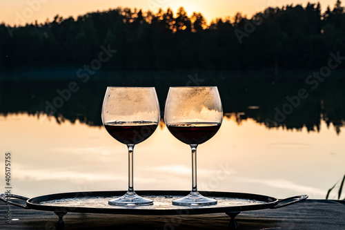 Two glasses of wine at sunset on a forest lake