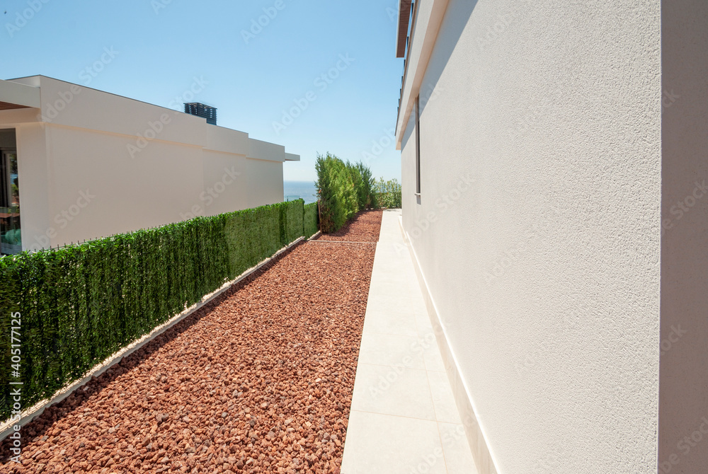 The facade of the modern house is from the side, and the organization of the yard and garden. Landscaping in the yard using natural jasper stone.