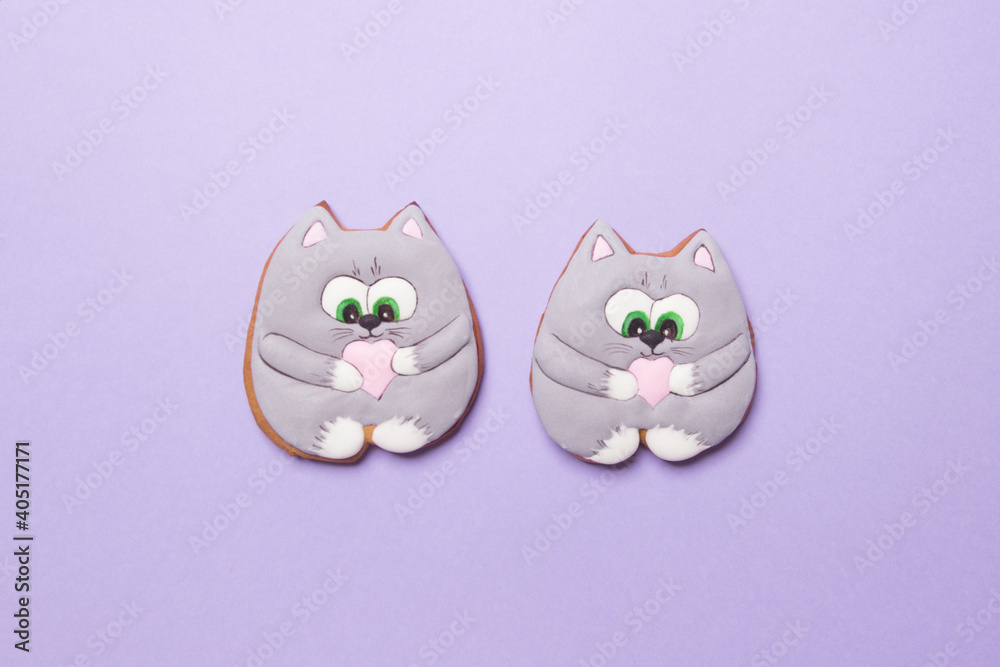two valentines cookies in form of cats on purple colored paper background