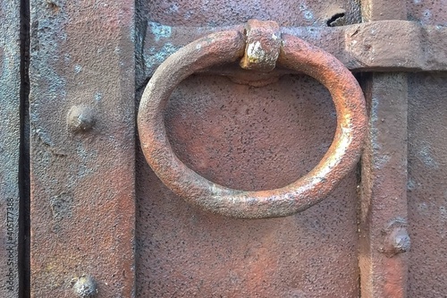 Fotografie Antique metal door knocker in the form of a ring on a wooden gate close-up