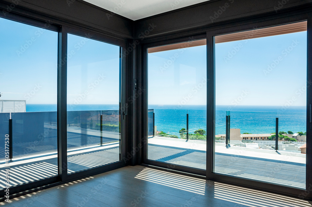 Fototapeta premium Empty room with large panoramic windows overlooking the sea. Room after major renovation.